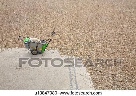 Stock Image - Street sweeper's cart on beach with tide advancing. Fotosearch