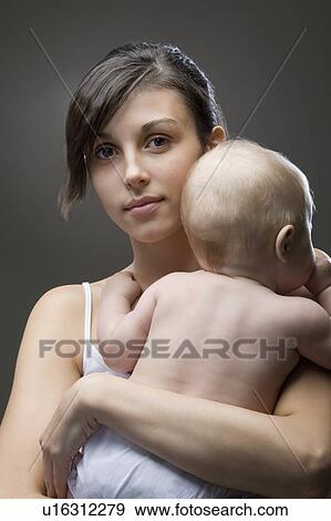 Stock Photo - Studio portrait of mother embracing baby boy. Fotosearch