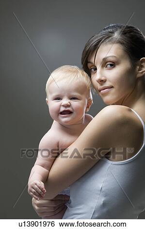 Stock Photograph - Studio portrait of mother embracing baby boy. Fotosearch