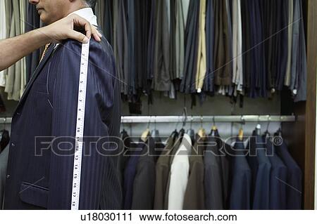 Stock Image - Tailor measuring business man for suit, side view. Fotosearch