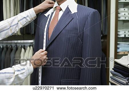 Stock Image - Tailor measuring business man for suit, mid section. Fotosearch
