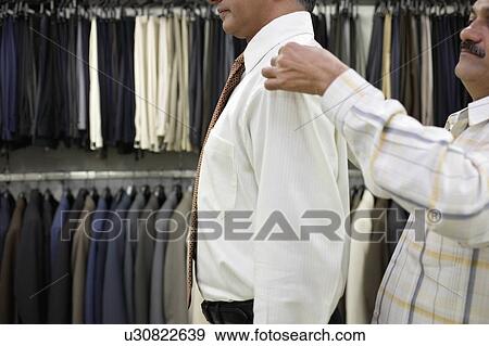 Stock Photo - Tailor measuring business man for suit, side view. Fotosearch