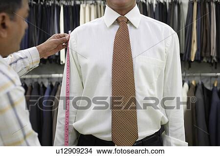 Picture - Tailor measuring business man with tape measure, mid section. Fotosearch