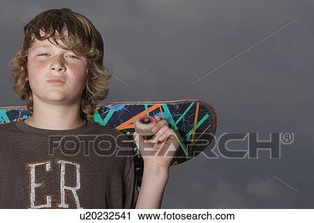 Teenage boy (13-15) holding skateboard, outdoors, portrait, low angle view View Large Photo Image Stock Image - Teenage boy (13-15) holding skateboard, outdoors, portrait, low angle view. Fotosearch