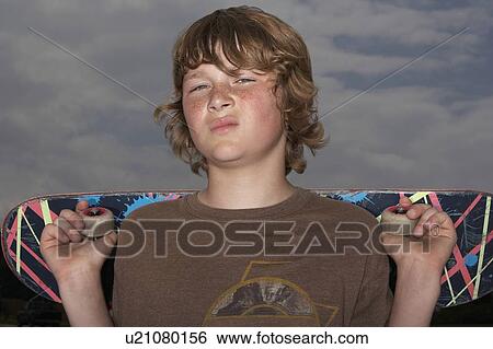 Teenage boy (13-15) holding skateboard, outdoors, portrait, close up View Large Photo Image Stock Photograph - Teenage boy (13-15) holding skateboard, outdoors, portrait, close up. Fotosearch