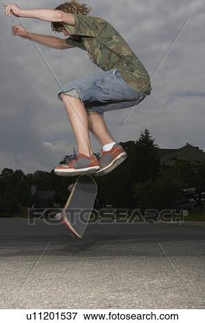 Teenage boy (16-17) jumping on skateboard on street, side view View Large Photo Image Stock Photo - Teenage boy (16-17) jumping on skateboard on street, side view. Fotosearch