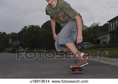 Teenage boy (16-17) skateboarding on street, low section View Large Photo Image Picture - Teenage boy (16-17) skateboarding on street, low section. Fotosearch