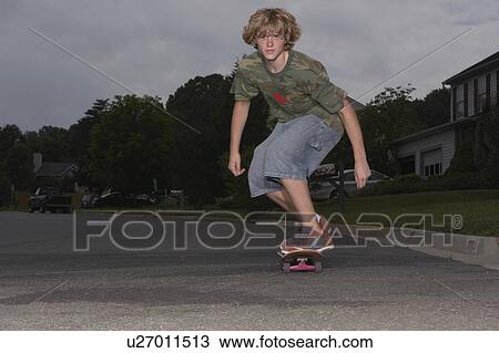Stock Image - Teenage boy (16-17) skateboarding on street. Fotosearch