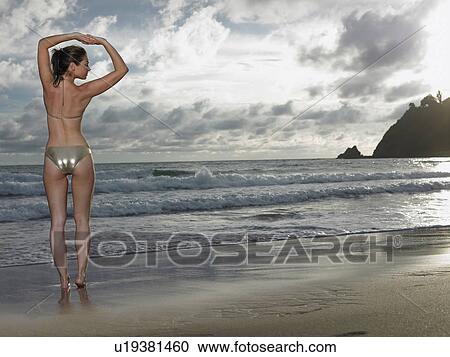 Stock Image - Thailand, young woman in bikini, stretching on beach. Fotosearch