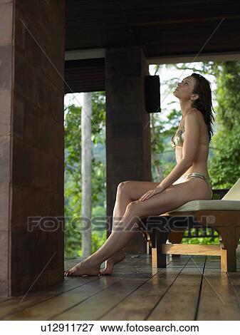 Stock Photo - Thailand, young woman in bikini relaxing on chair. Fotosearch