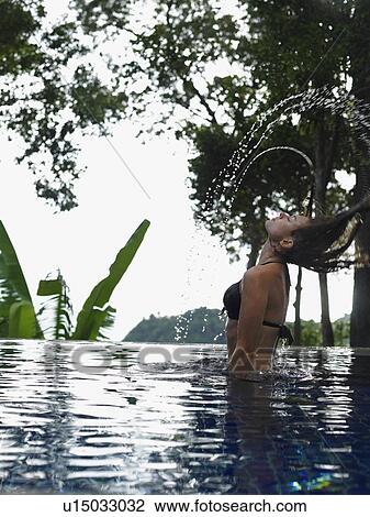 Stock Image - Thailand, young woman relaxing in swimming pool. Fotosearch