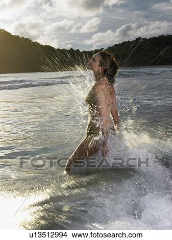 Picture - Thailand, young woman splashing in sea. Fotosearch