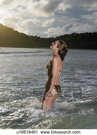 Stock Image - Thailand, young woman standing in sea. Fotosearch