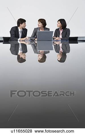Stock Photo - Three business colleagues using laptop at conference table. Fotosearch