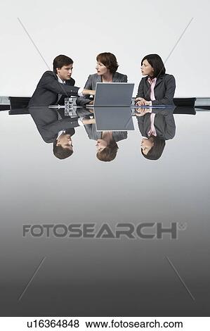 Stock Photo - Three business colleagues using laptop at conference table. Fotosearch
