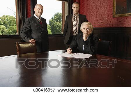 Stock Photo - Three businessmen in boardroom. Fotosearch