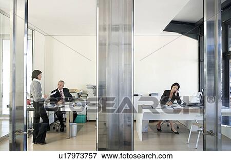 Stock Photo - Three businesspeople in office, working.. Fotosearch