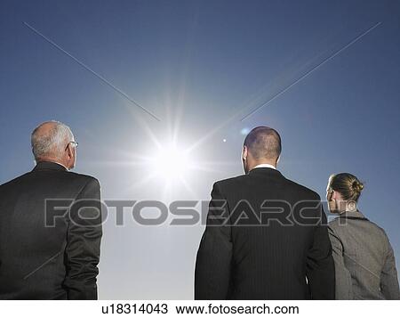 Stock Image - Three Businesspeople Looking at Sun. Fotosearch