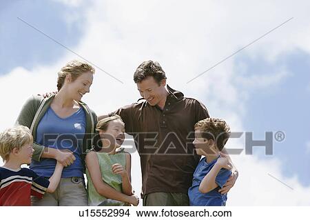 Picture - Three children (7-9) with parents outdoors, low angle view.. Fotosearch