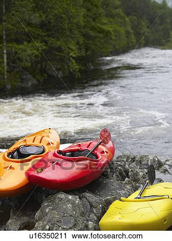 Stock Image - Three kayaks by river. Fotosearch
