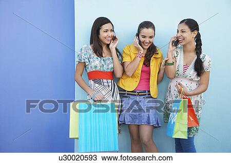 Three teenage girls (16-17) using mobile phones standing against wall View Large Photo Image Stock Image - Three teenage girls (16-17) using mobile phones standing against wall. Fotosearch