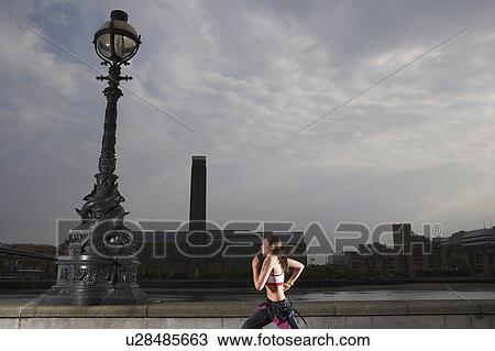 Stock Image - Triathlon athlete running along river embankment, London, England, side view. Fotosearch