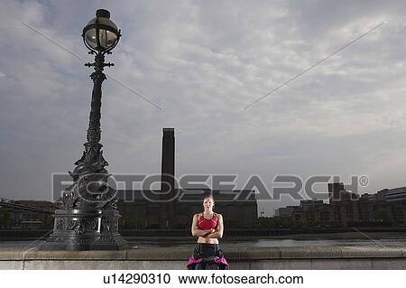 Stock Image - Triathlon athlete standing by river embankment, London, England. Fotosearch