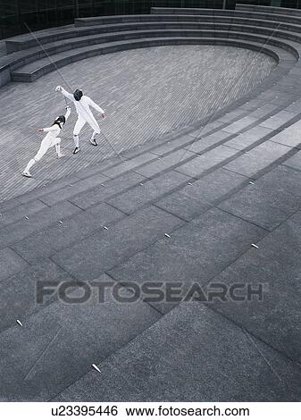 Stock Photograph - Two athletes fencing in the Scoop amphitheatre, London, England, elevated view. Fotosearch