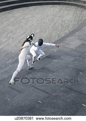 Stock Image - Two athletes fencing on steps of the Scoop amphitheatre, London, England, elevated view. Fotosearch