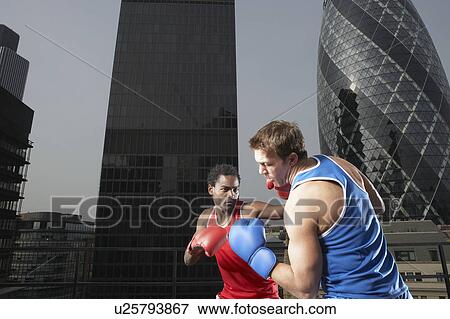 Stock Photo - Two boxers fighting amongst downtown buildings, low angle view, London, England. Fotosearch