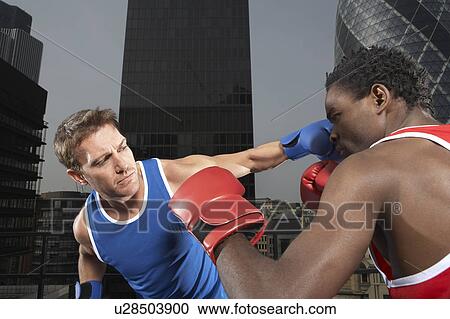 Stock Image - Two boxers punching amongst downtown buildings, London, England. Fotosearch