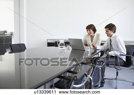 Two business colleagues using laptop at conference table View Large Photo Image Stock Image - Two business colleagues using laptop at conference table. Fotosearch