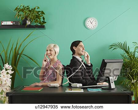 Stock Photography - Two business people talking on entangled phones in office. Fotosearch