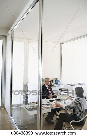 Two businesspeople sitting at desk in office, elevated view. View Large Photo Image Stock Image - Two businesspeople sitting at desk in office, elevated view.. Fotosearch