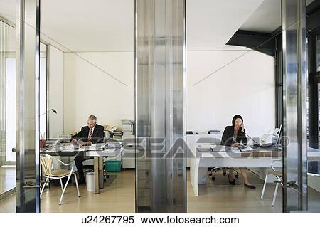 Stock Photography - Two Businesspeople Working in Office, front view.. Fotosearch