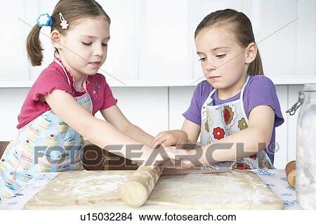 Two girls (5-6) rolling dough View Large Photo Image Picture - Two girls (5-6) rolling dough. Fotosearch