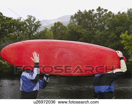 Stock Photograph - Two men carrying kayak outdoors. Fotosearch