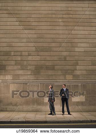 Picture - Two men on sidewalk, looking up. Fotosearch