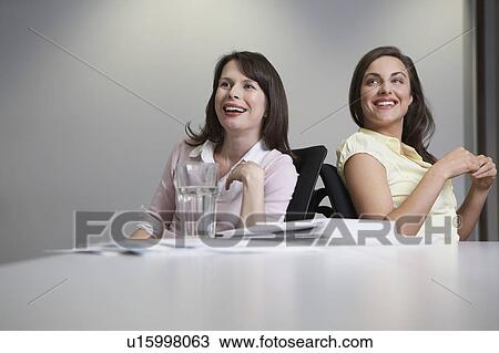 Stock Image - Two women sitting at desk. Fotosearch