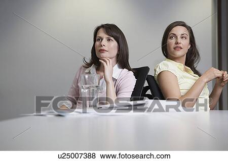 Stock Photo - Two women sitting at desk. Fotosearch