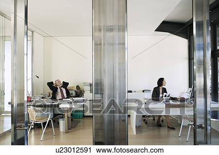 View through transparent doors of businesswoman working in office, while businessman relaxes. View Large Photo Image Stock Image - View through transparent doors of businesswoman working in office, while businessman relaxes.. Fotosearch