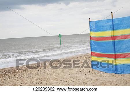Stock Image - Windbreak pegged to shingle with tide marker at sea. Fotosearch