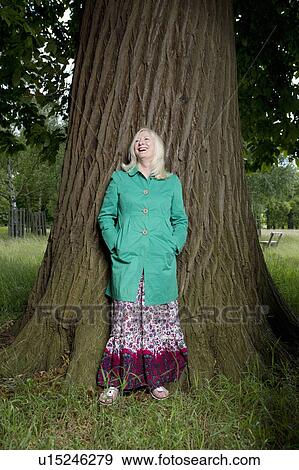 Stock Photo - Woman Leaning on a Tree Trunk. Fotosearch