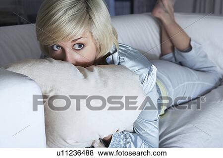 Stock Photo - Woman lying on sofa, looking on side. Fotosearch