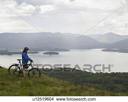 Picture - Woman on bicycle near lake. Fotosearch
