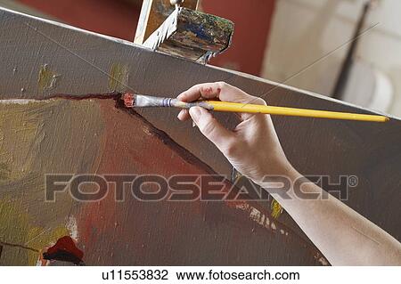 Stock Image - Woman painting on canvas, close-up of hand. Fotosearch