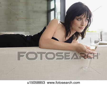 Woman reclining on couch with champagne in living room View Large Photo Image Stock Image - Woman reclining on couch with champagne in living room. Fotosearch