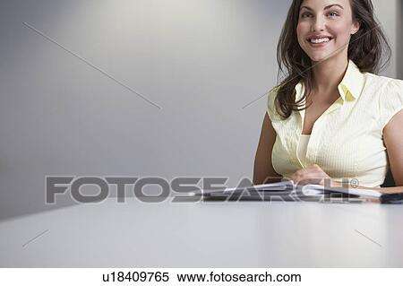 Stock Photography - Woman sitting at desk and smiling. Fotosearch