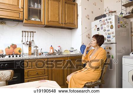 Stock Photo - Woman smoking in kitchen. Fotosearch