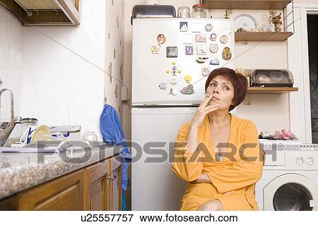 Stock Photo - Woman smoking in kitchen. Fotosearch